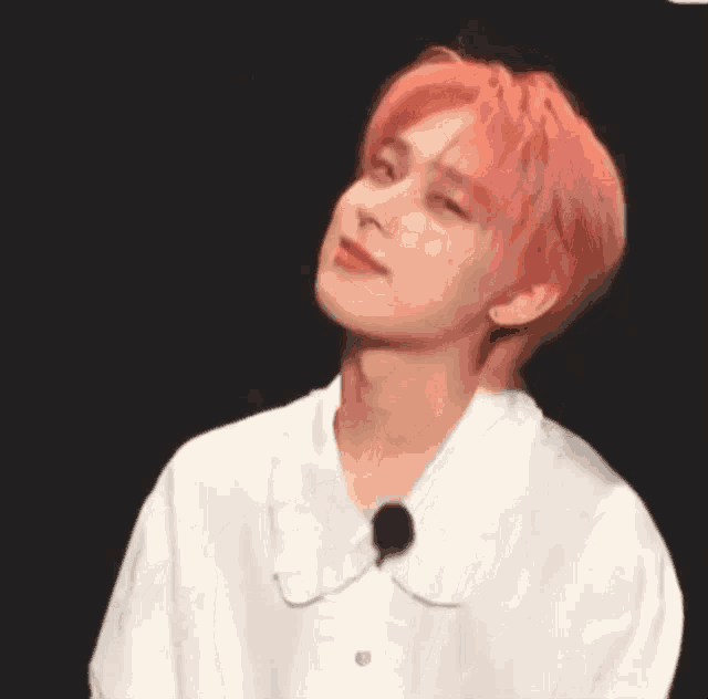 a close up of a person with pink hair wearing a white shirt .