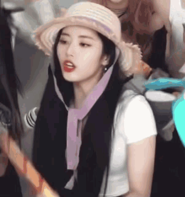 a woman wearing a hat and a scarf around her neck is holding a guitar .