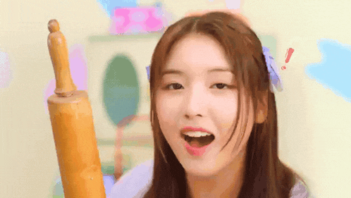 a girl is holding a wooden rolling pin in her right hand