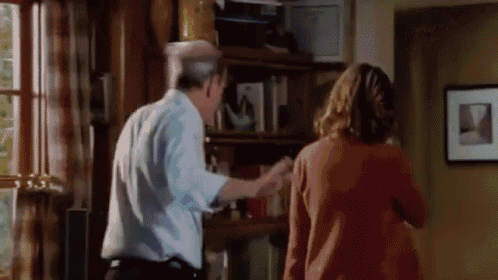 a man and a woman are standing in a living room talking to each other .