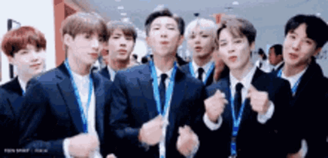a group of men in suits and ties are standing next to each other and making funny faces .