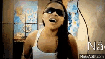 a woman wearing sunglasses and a tank top is singing a song .