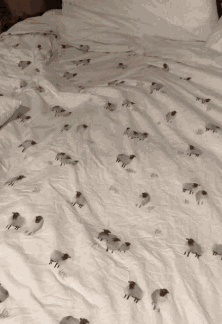 a bed with a blanket with sheep printed on it