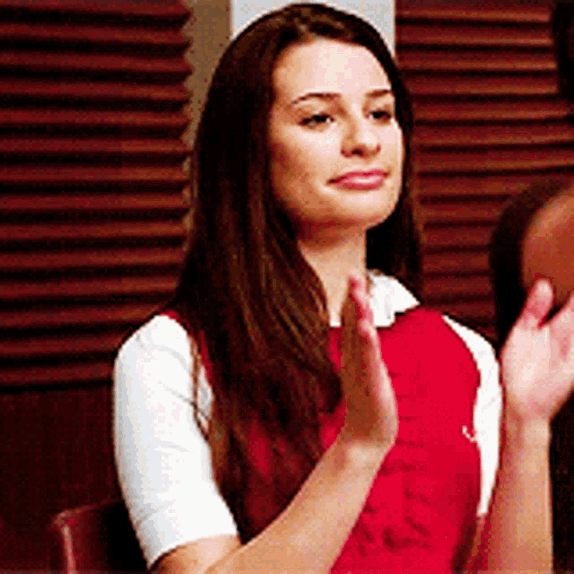 a woman in a red shirt and white shirt is clapping her hands