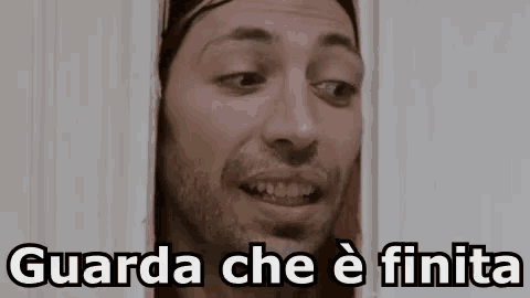 a man with a beard is looking out of a doorway with the words `` guarda che e finita '' .