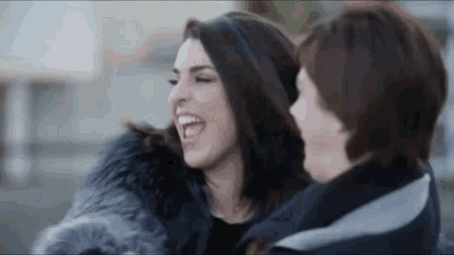 a woman in a fur coat laughs with another woman