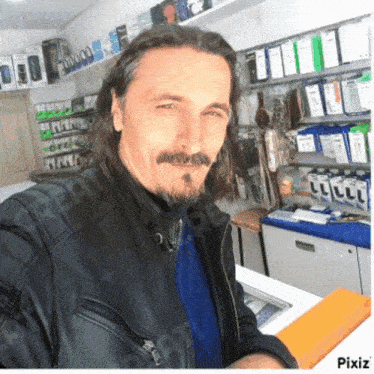 a man with long hair and a beard is standing in a store with pixiz written on the bottom right
