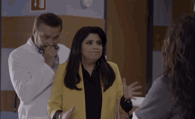 a woman in a yellow jacket is talking to a man in a white lab coat