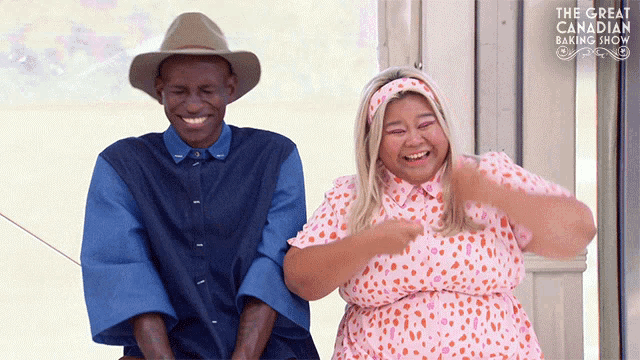 a man and woman are laughing in front of the great canadian baking show