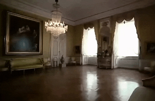 an empty room with a chandelier and a painting on the wall