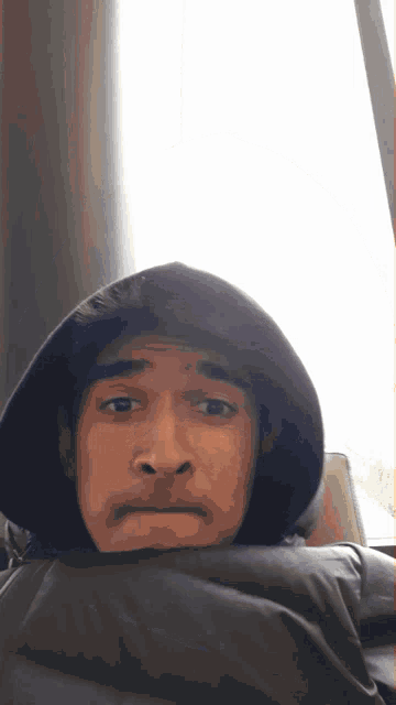 a young man wearing a hooded jacket looks at the camera