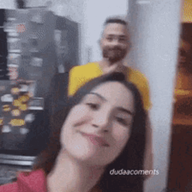 a man in a yellow shirt is standing behind a woman who is smiling