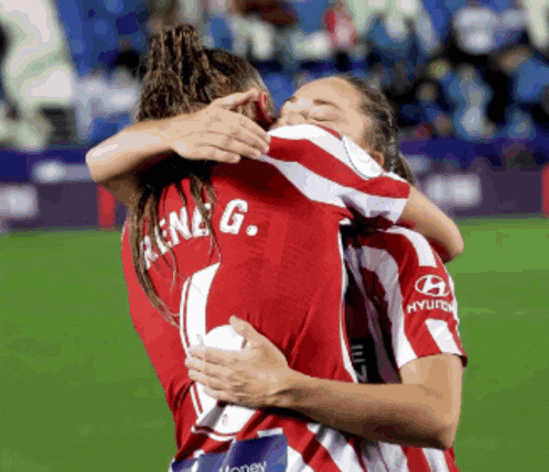 two female soccer players hugging each other and one has rene g. on her back