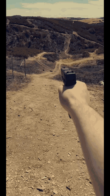 a person is pointing a gun at a dirt hillside