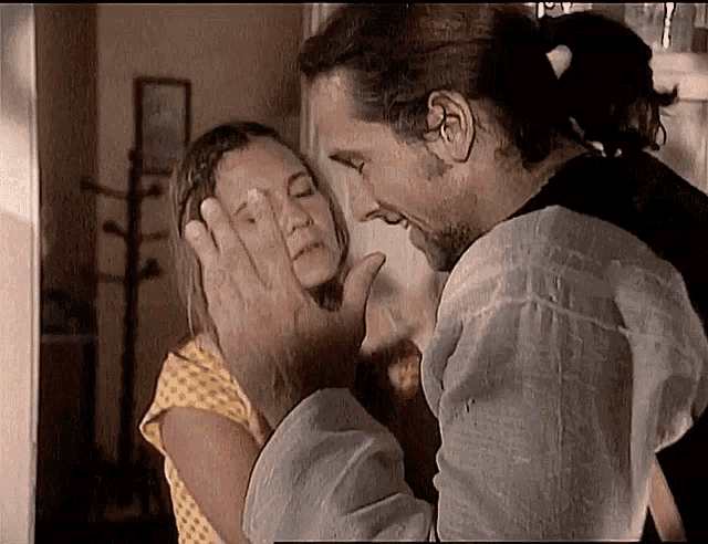 a man is touching a woman 's face with his hand