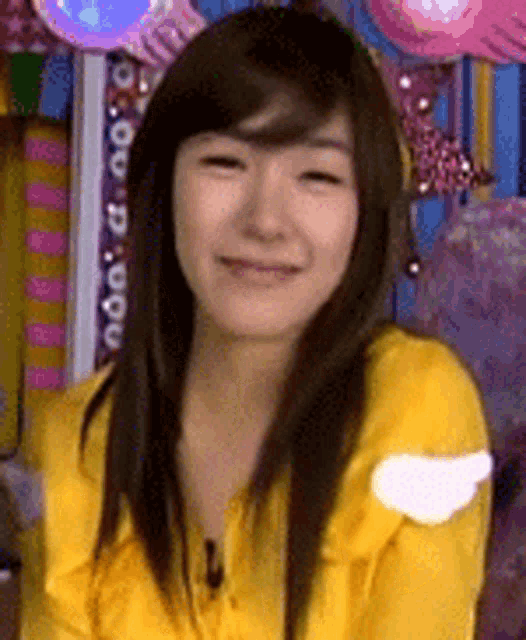 a woman in a yellow shirt is smiling and looking at the camera .