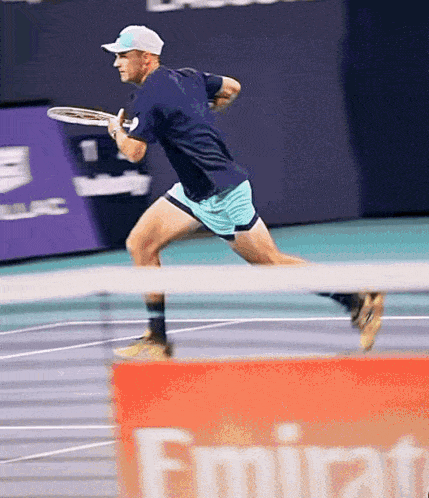 a man is playing tennis in front of an emirates banner