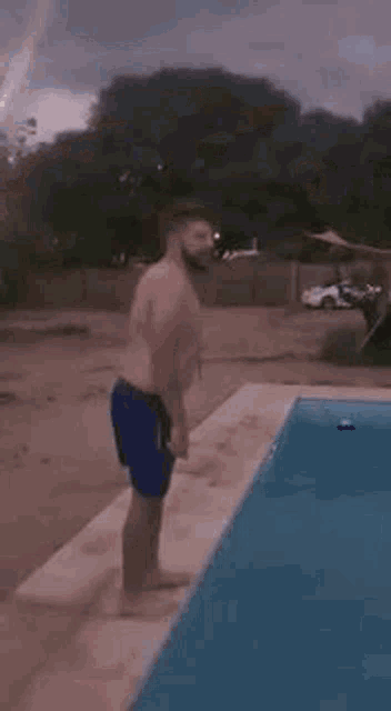 a shirtless man is jumping into a swimming pool .