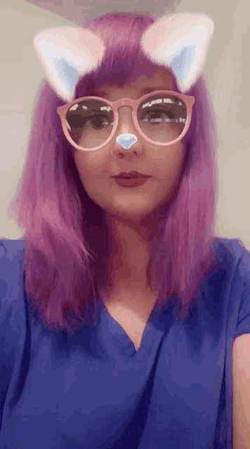 a woman with purple hair is wearing cat ears sunglasses and a blue shirt