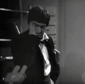 a black and white photo of a man in a tuxedo talking on a phone