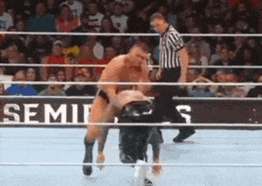 two men are wrestling in a wrestling ring with a referee .