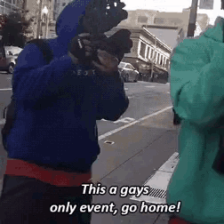 a man in a blue jacket is talking on a cell phone and says this a gays only event go home