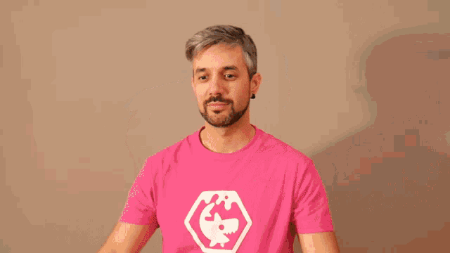 a man wearing a pink trans shirt holds a piggy bank