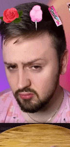 a man with a beard is wearing a pink shirt with a rose and cotton candy in his hair ..