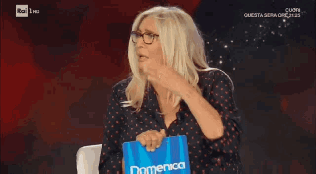 a woman covering her mouth while holding a sign that says domenica on it