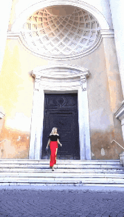 a woman in red pants is walking down the stairs of a church