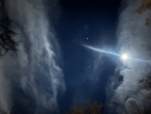 a bright light shines through the clouds in the night sky