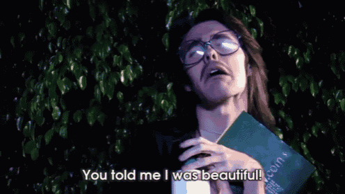 a man with glasses is holding a book and saying you told me i was beautiful