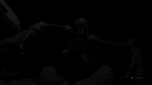 a person is standing in a dark room with a gray wall .