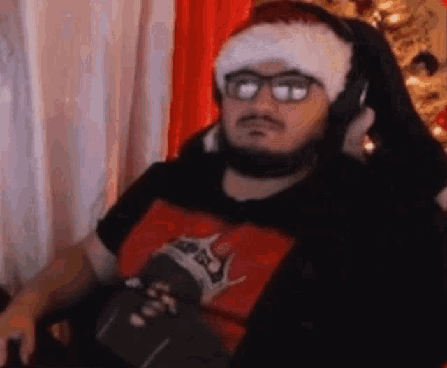 a man with a beard is wearing a santa hat and headphones while sitting in a chair .