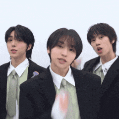 three young men in suits and ties are posing for a picture .