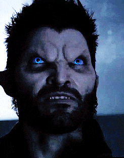 a close up of a man 's face with a beard and blue eyes