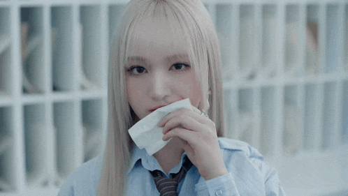a woman with blonde hair wearing a blue shirt and tie has red lipstick on her lips