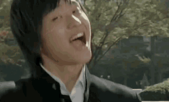 a young man in a school uniform is making a funny face with his tongue out .