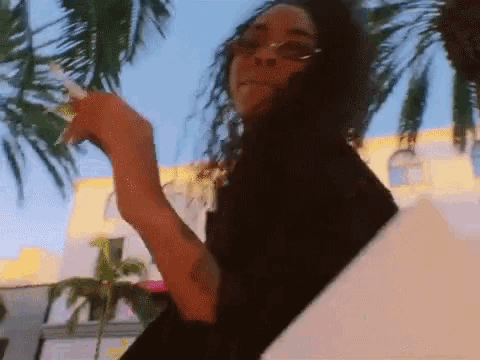 a woman smoking a cigarette in front of palm trees