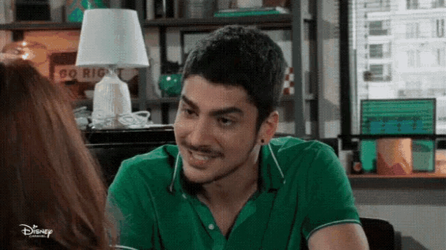 a man in a green shirt is smiling at a woman while sitting at a table .