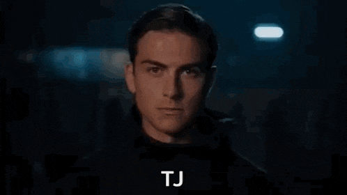 a close up of venom 's face in a dark room with the words tj written on the bottom .