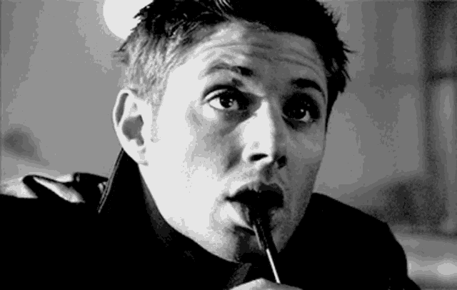 a man is holding a pen in his mouth and making a funny face .
