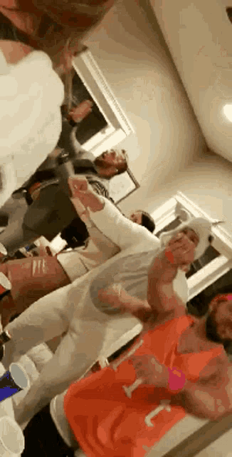 a group of people are dancing in a room and one of them is wearing an orange shirt with the letter j on it .