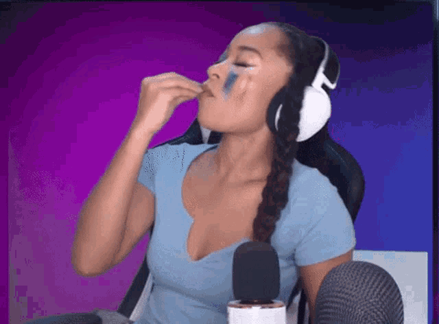 a woman wearing headphones is sitting in front of a microphone and eating something .