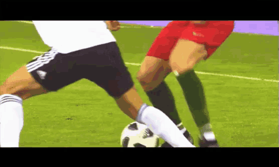a soccer player wearing adidas shorts is kicking the ball