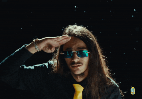 a man with long hair wearing sunglasses and a black shirt with a yellow tie