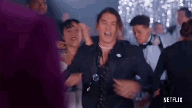 a man in a suit is dancing in a crowd of people at a party in a netflix ad .