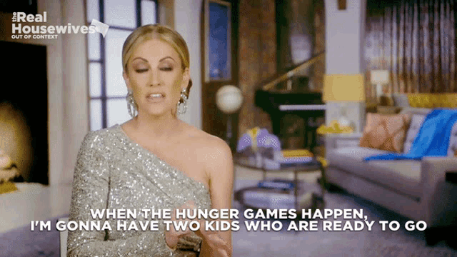 a woman in a silver dress is talking about hunger games