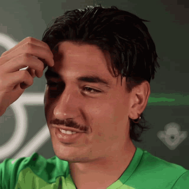 a man with a mustache wearing a green shirt is smiling