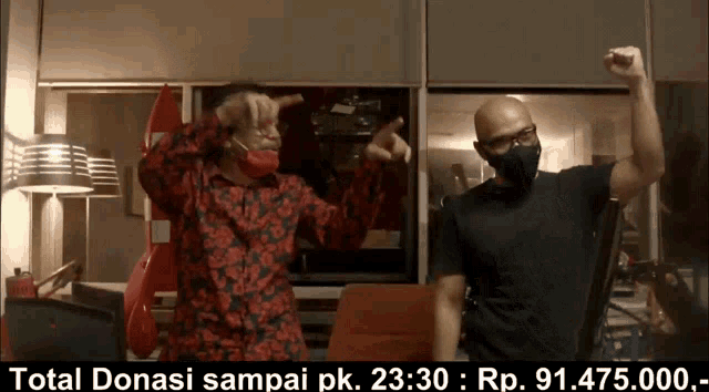 two men wearing masks are dancing in front of a sign that says total donasi sampai pk.